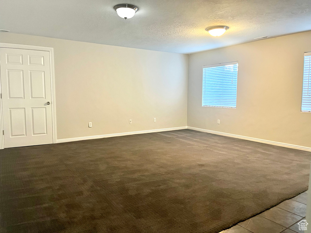 Spare room featuring a textured ceiling and dark carpet