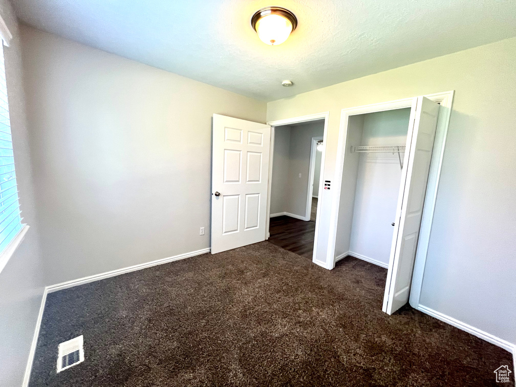 Unfurnished bedroom with a closet and dark colored carpet