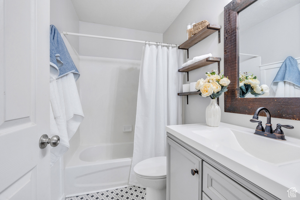 Full bathroom featuring tile flooring, shower / tub combo, toilet, vaulted ceiling, and vanity