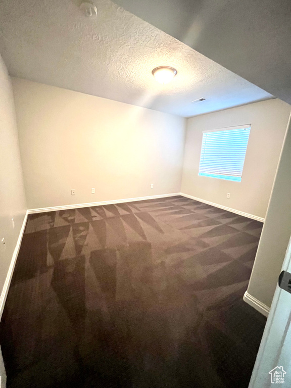 Empty room with a textured ceiling and carpet flooring