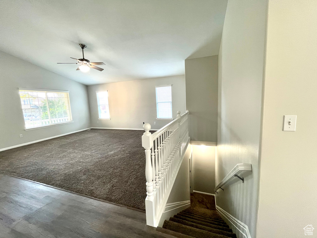 Stairway with vaulted ceiling, ceiling fan, plenty of natural light, and carpet flooring