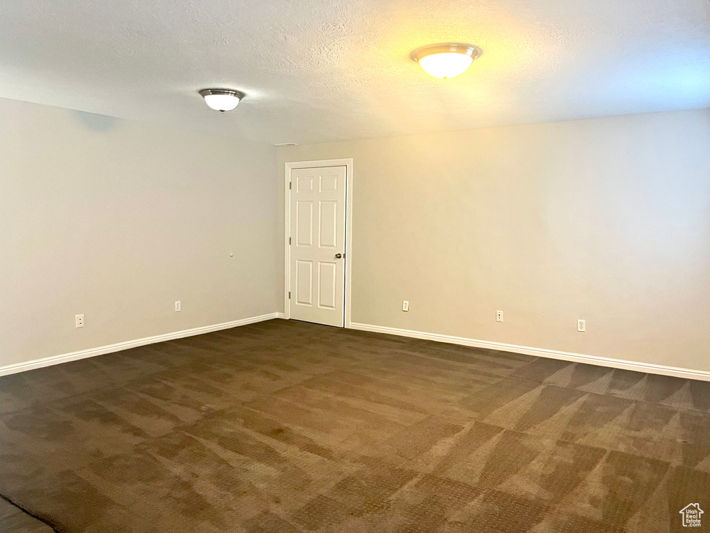 Unfurnished room with dark carpet and a textured ceiling