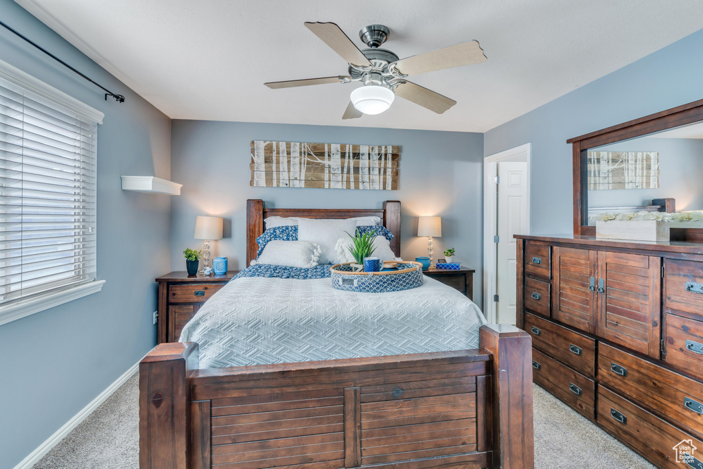 Carpeted bedroom with ceiling fan and multiple windows