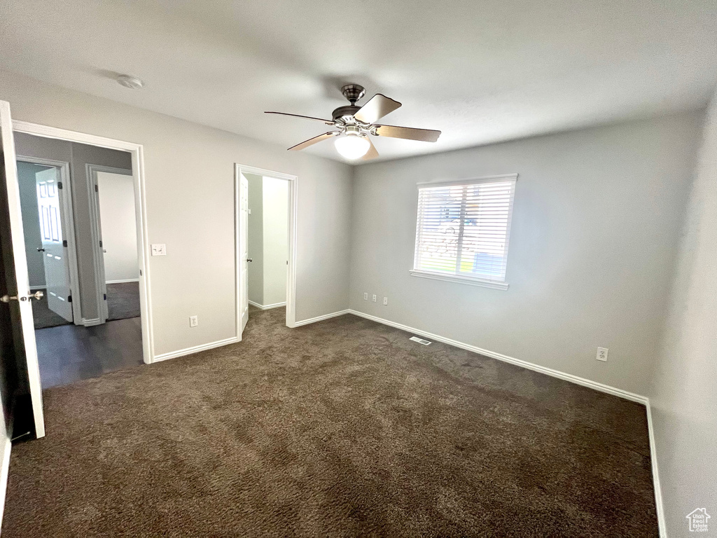 Unfurnished bedroom featuring ceiling fan and dark carpet