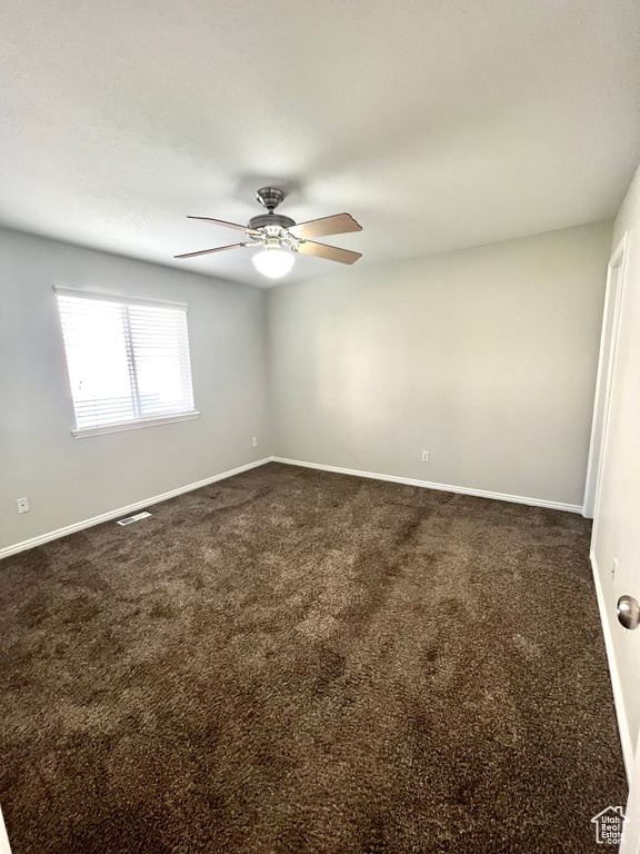 Carpeted spare room featuring ceiling fan