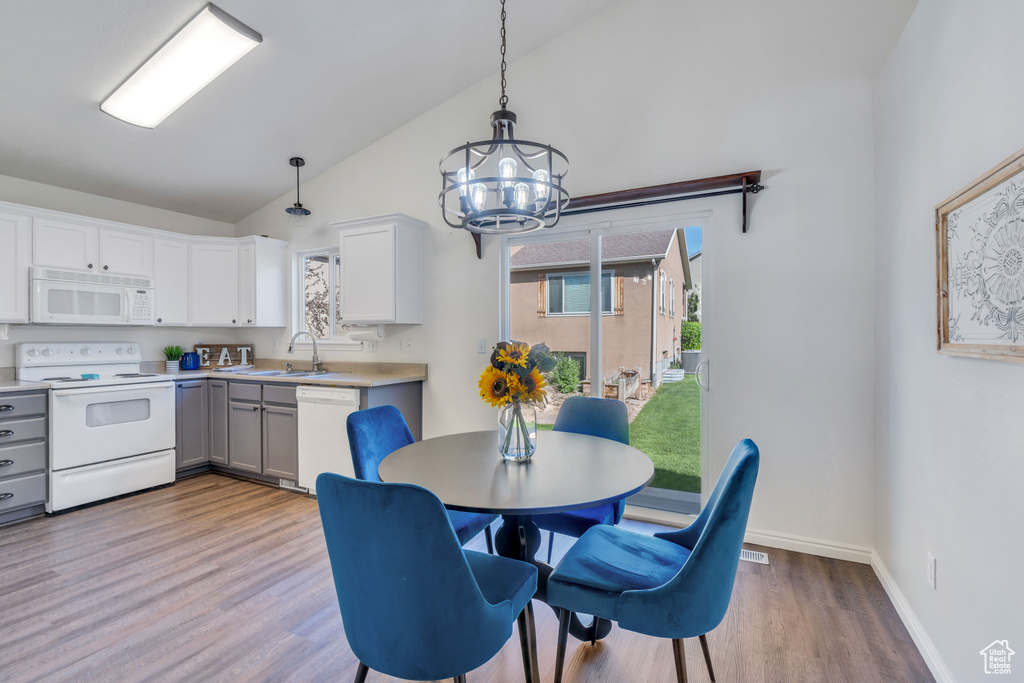 Dining area with high vaulted ceiling, hardwood / wood-style floors, a notable chandelier, and sink