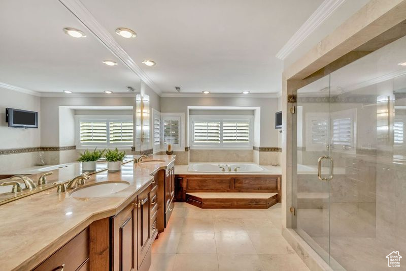 Bathroom with a wealth of natural light, dual sinks, oversized vanity, and plus walk in shower