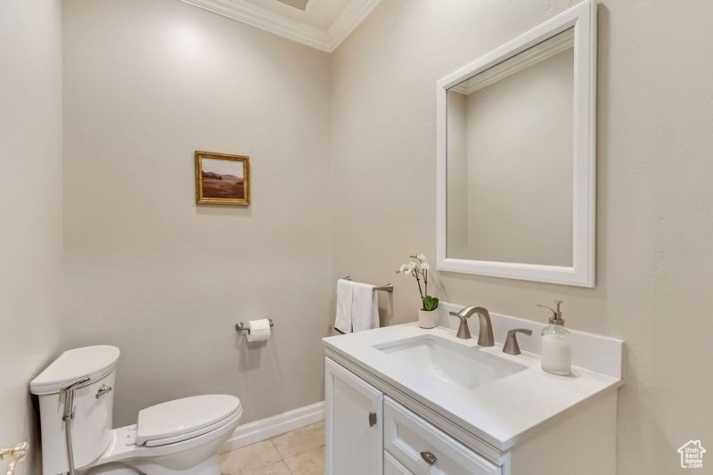Bathroom featuring vanity, tile floors, toilet, and crown molding