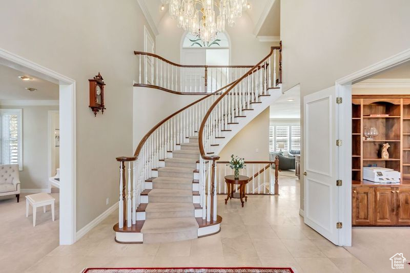 Stairway featuring plenty of natural light, crown molding, and light tile floors