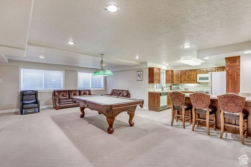 Playroom with light carpet, billiards, and a textured ceiling