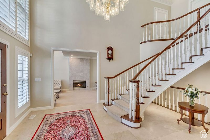 Foyer entrance featuring plenty of natural light, ornamental molding, a tile fireplace, and a high ceiling