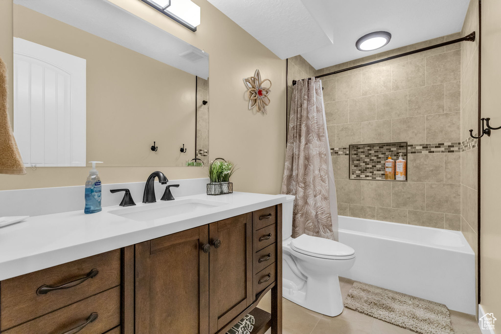 Full bathroom with toilet, tile floors, vanity, and shower / tub combo with curtain