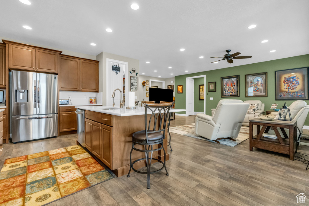 Kitchen with a kitchen island with sink, appliances with stainless steel finishes, sink, hardwood / wood-style flooring, and ceiling fan