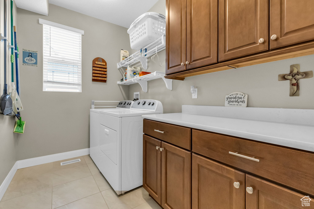 Laundry room with cabinets, washer hookup, light tile floors, and washer and dryer