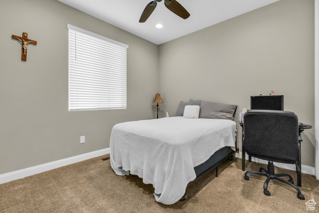 Bedroom with carpet flooring, ceiling fan, and multiple windows