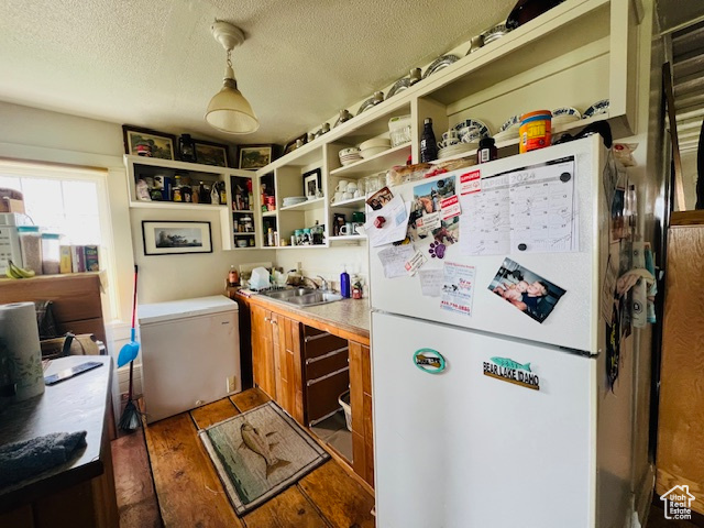 Kitchen featuring fridge, white refrigerator, dark wood-type flooring, sink, and a textured ceiling