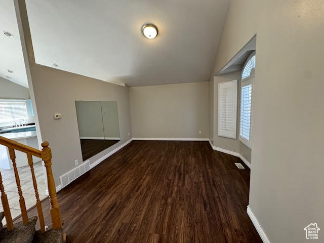 Spare room with dark hardwood / wood-style floors and vaulted ceiling