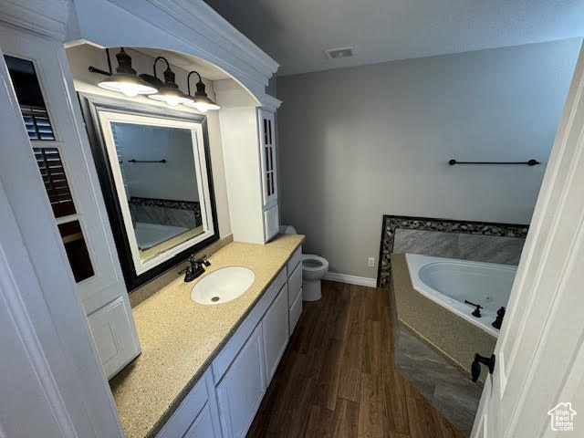 Bathroom featuring hardwood / wood-style floors, vanity, toilet, and a bathtub