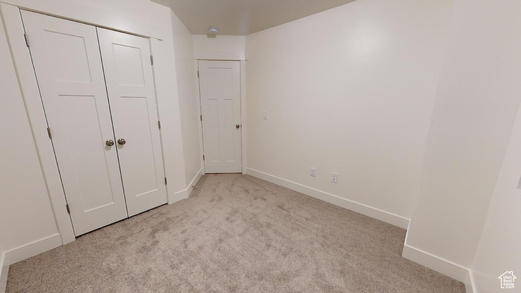 Unfurnished bedroom with light colored carpet and a closet