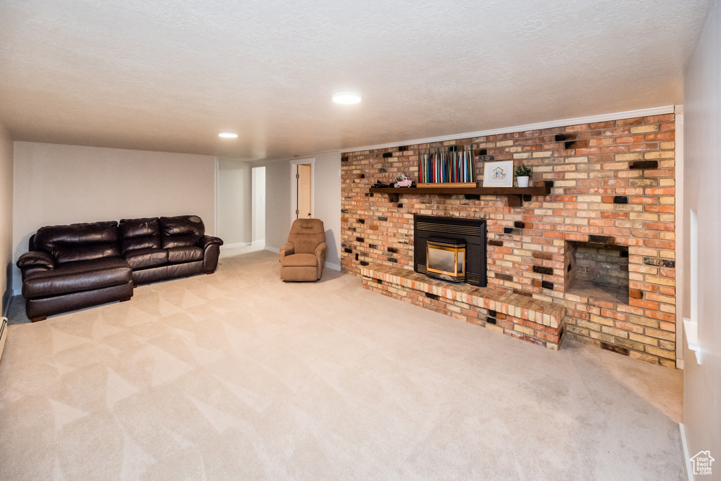 Living room featuring a textured ceiling, carpet, and a brick fireplace