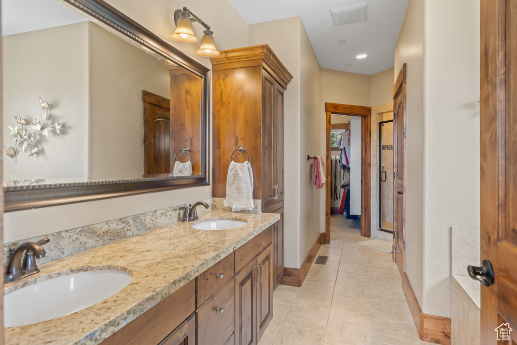 Bathroom featuring vanity with extensive cabinet space, dual sinks, and tile floors