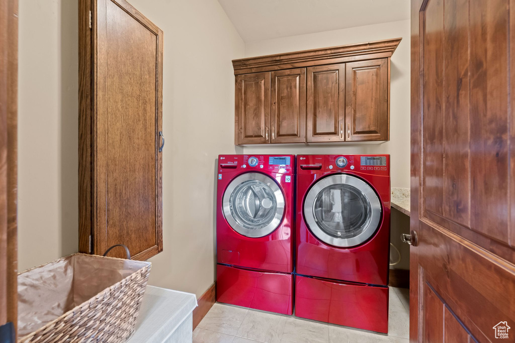 Laundry room featuring cabinets, independent washer and dryer, and light tile floors