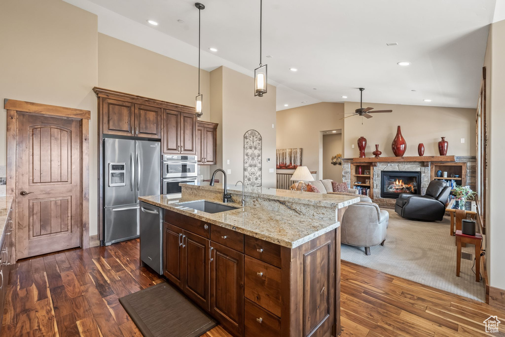 Kitchen featuring sink, decorative light fixtures, dark hardwood / wood-style flooring, stainless steel appliances, and an island with sink