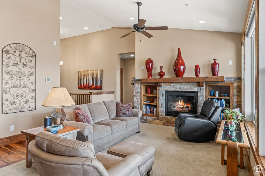 Living room featuring hardwood / wood-style flooring, high vaulted ceiling, ceiling fan, and a fireplace