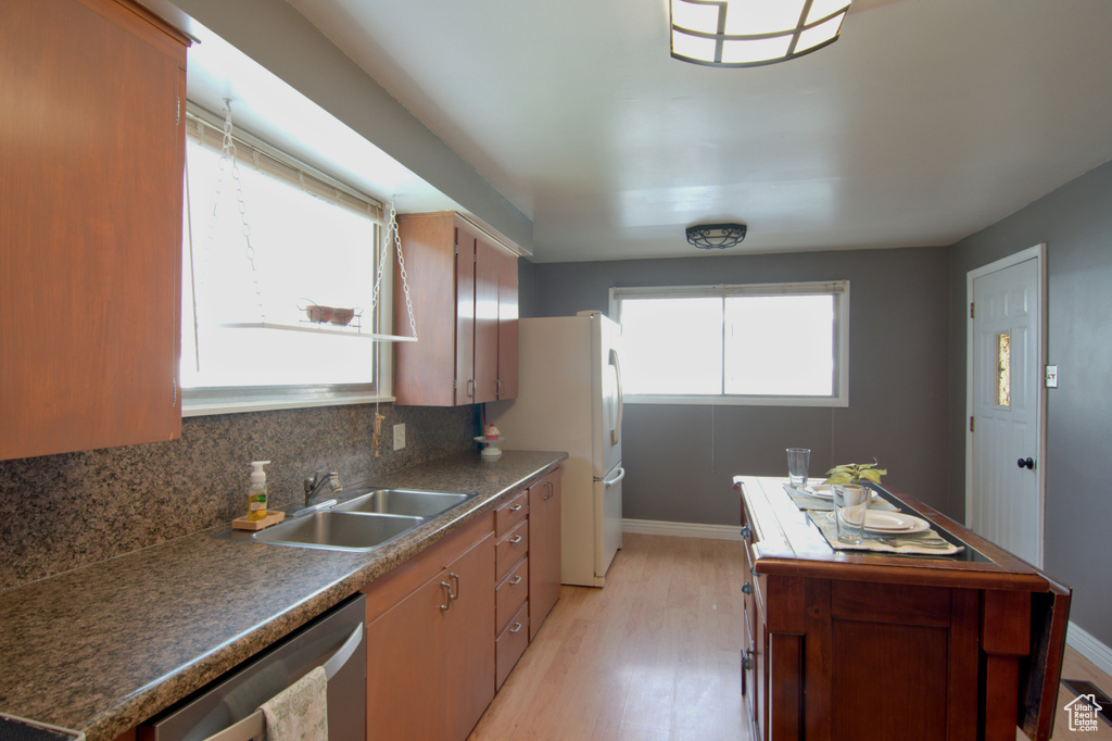 Kitchen featuring white fridge, backsplash, light hardwood / wood-style flooring, dishwasher, and sink