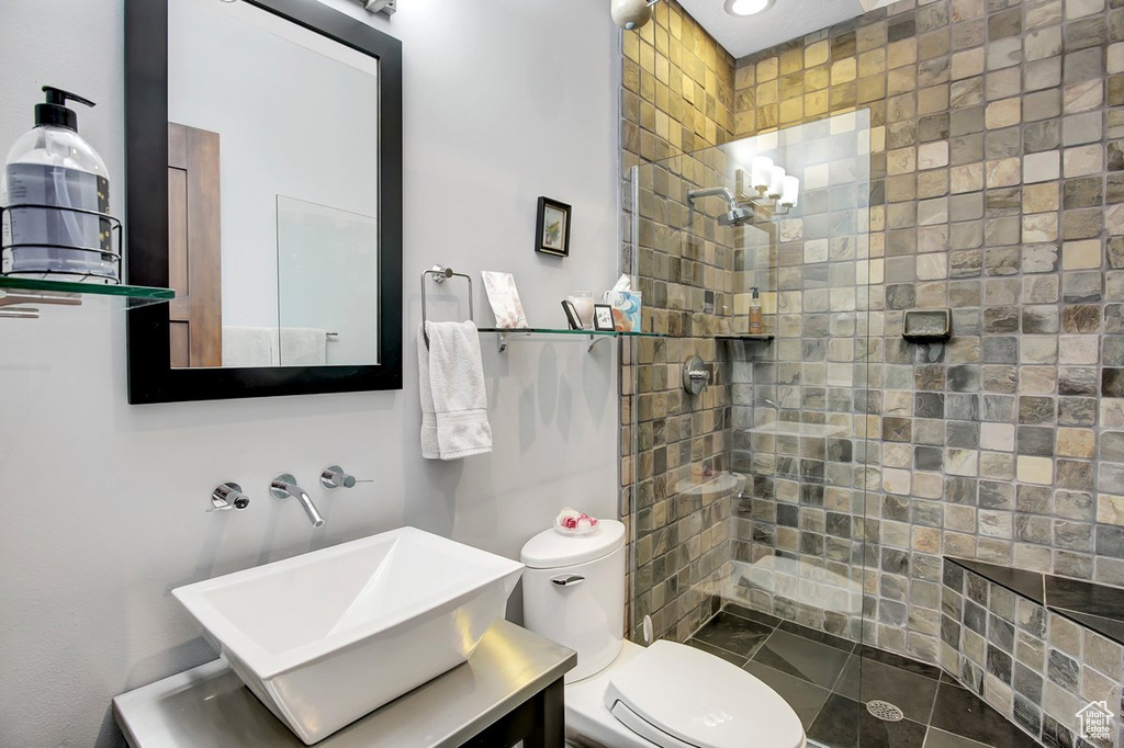 Bathroom featuring vanity, toilet, and tiled shower