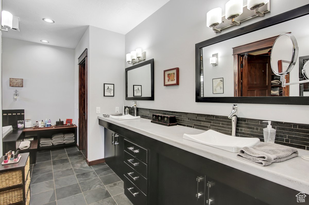 Bathroom with backsplash, tile floors, and double sink vanity