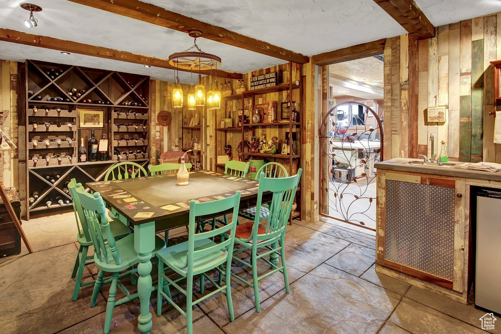 Interior space with sink, wood walls, light tile flooring, and beam ceiling