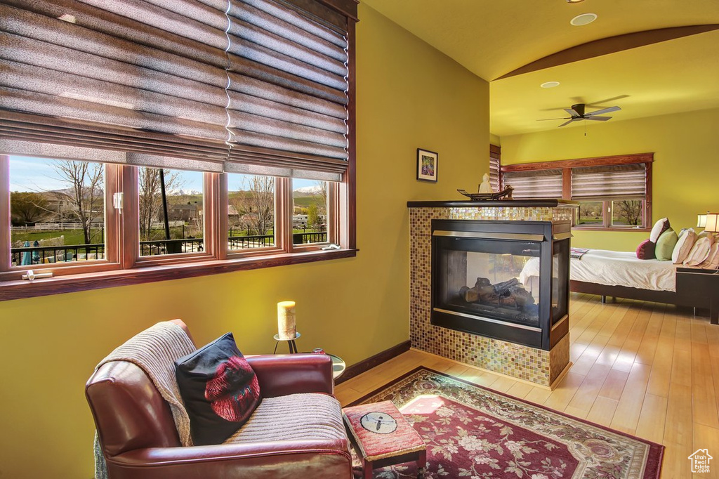 Living room featuring wood-type flooring, ceiling fan, and a tiled fireplace