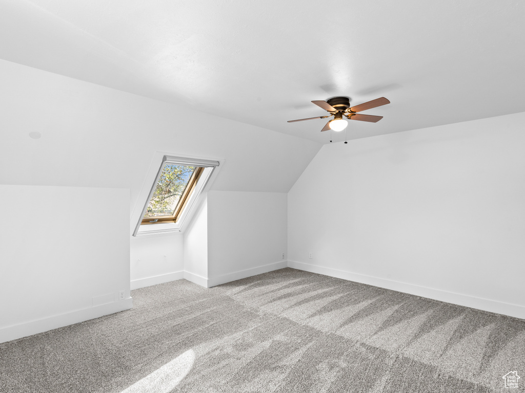 Bonus room featuring lofted ceiling with skylight, ceiling fan, and carpet floors