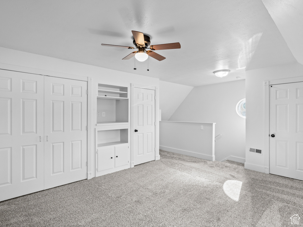 Additional living space featuring ceiling fan, carpet floors, and lofted ceiling
