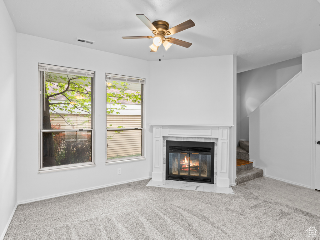 Unfurnished living room featuring ceiling fan, a tiled fireplace, and carpet flooring