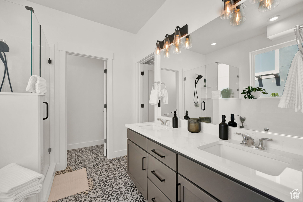 Bathroom with a shower with door, tile floors, and double sink vanity