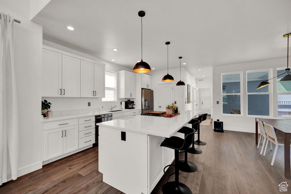 Kitchen with white cabinets, appliances with stainless steel finishes, a kitchen island, and a wealth of natural light