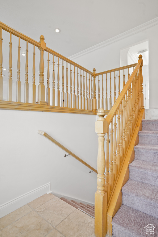 Stairway featuring crown molding and tile floors