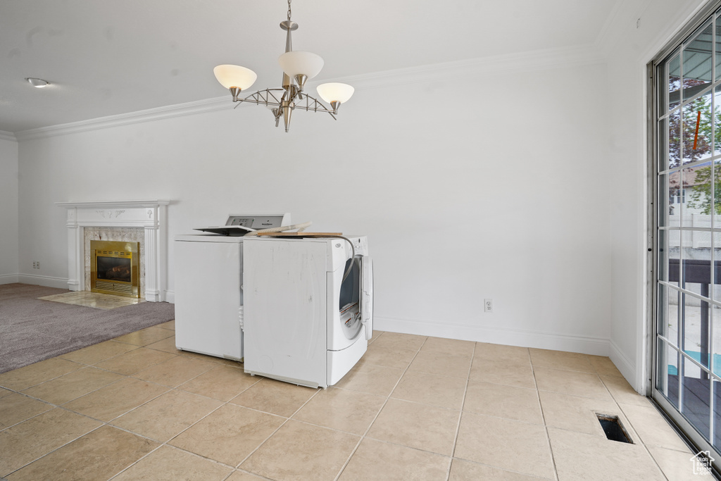 Washroom featuring light tile flooring, crown molding, and washer and clothes dryer