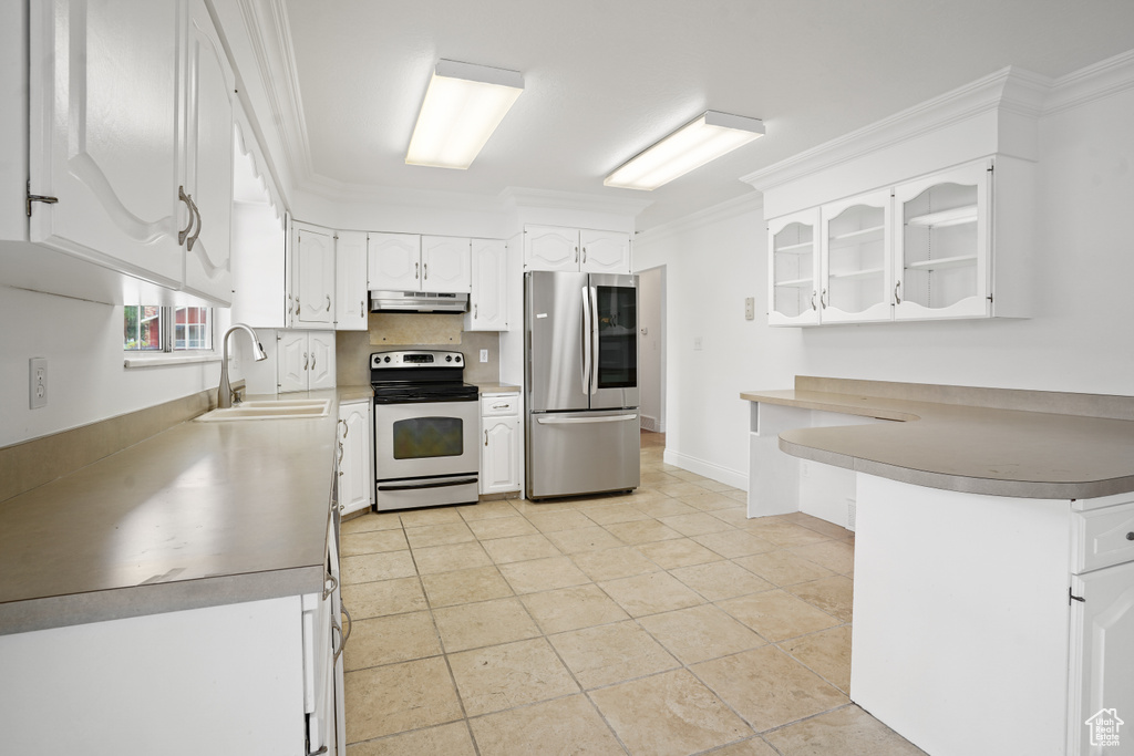 Kitchen with electric stove, stainless steel refrigerator, white cabinets, sink, and light tile floors