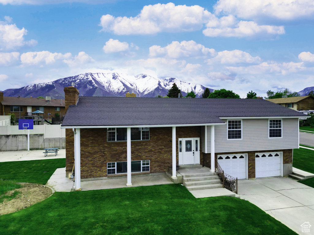 View of front of home featuring a mountain view, a garage, and a front lawn
