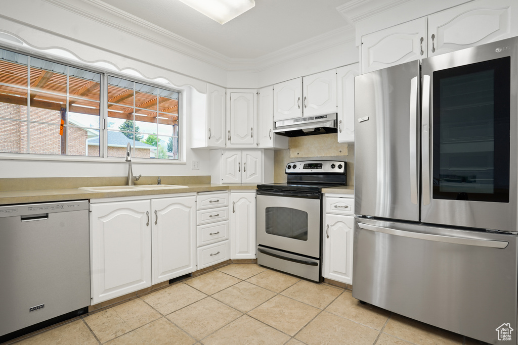 Kitchen featuring light tile flooring, crown molding, white cabinetry, stainless steel appliances, and sink