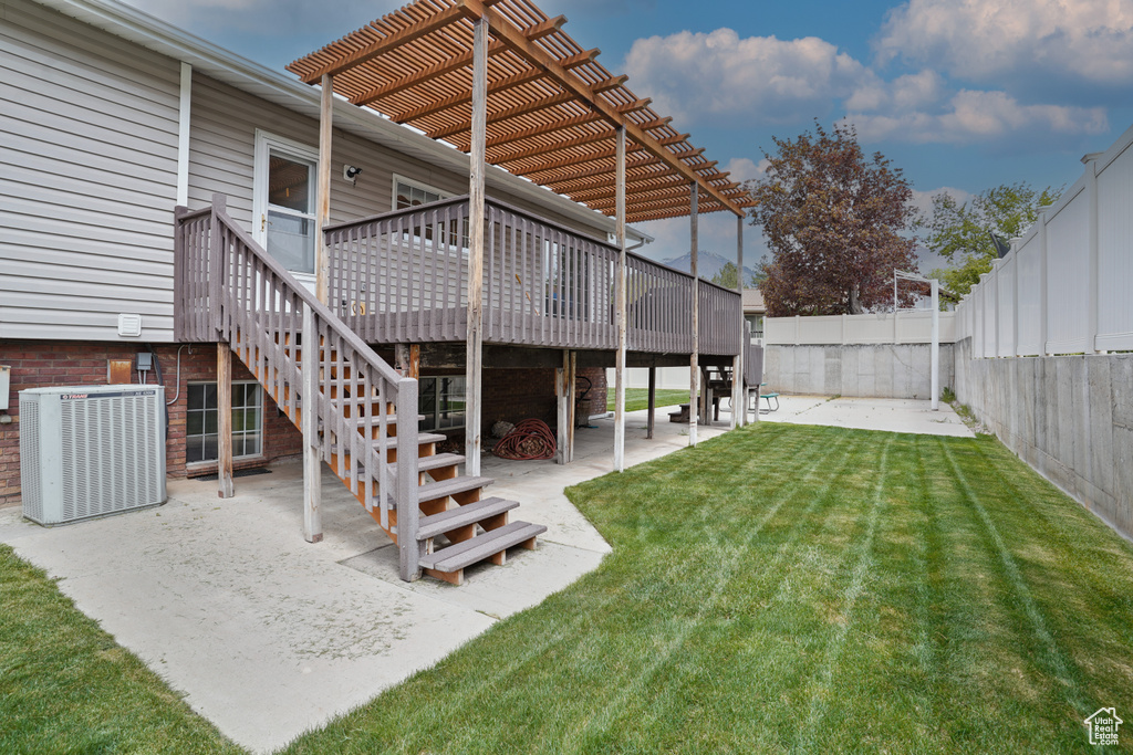 View of yard featuring central AC unit, a wooden deck, a pergola, and a patio