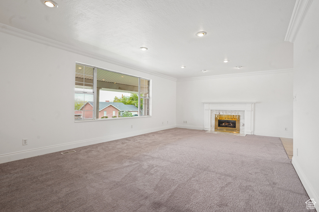 Unfurnished living room featuring ornamental molding, carpet flooring, and a fireplace