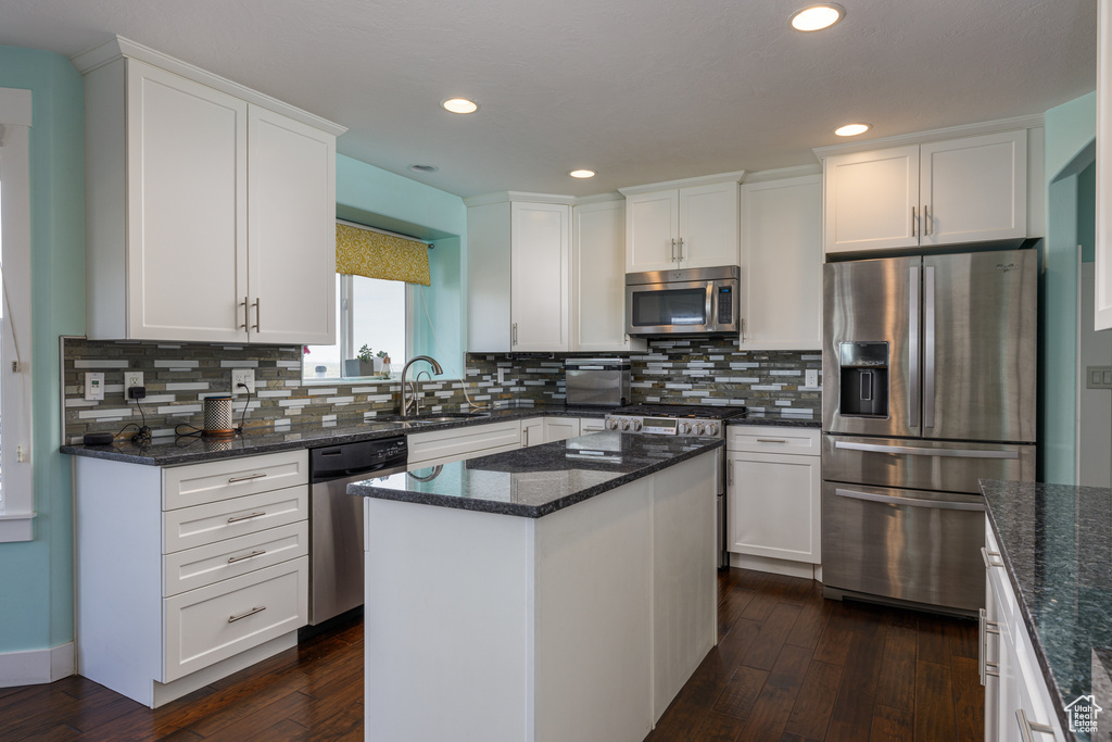 Kitchen featuring a center island, dark wood-type flooring, stainless steel appliances, and white cabinetry