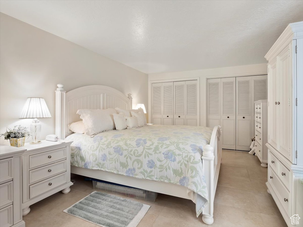 Bedroom with multiple closets and light tile floors