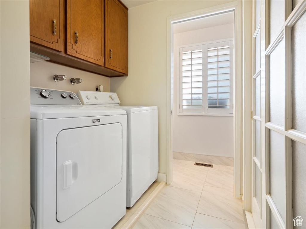 Laundry room with cabinets, separate washer and dryer, light tile flooring, and washer hookup