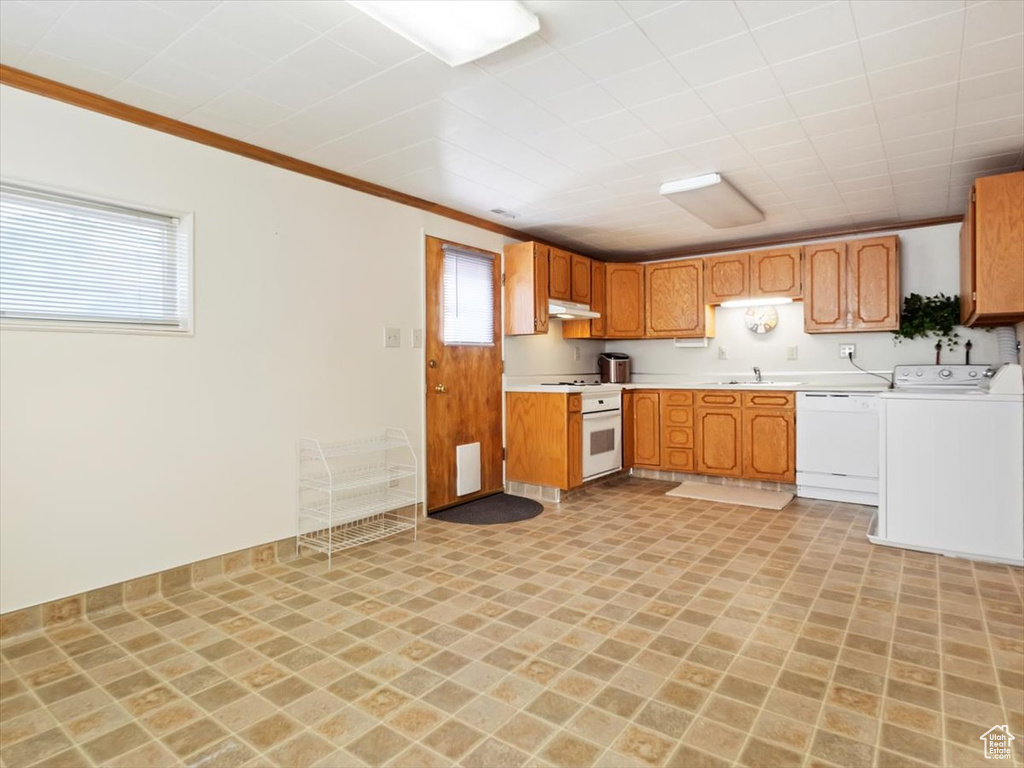 Kitchen with sink, crown molding, white dishwasher, and light tile floors