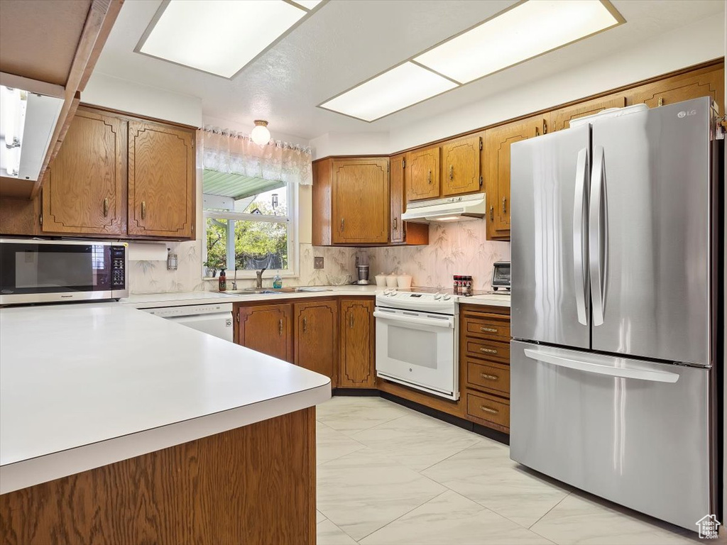 Kitchen with sink, appliances with stainless steel finishes, tasteful backsplash, and light tile floors